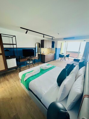 A modern hotel room with a large bed, a desk, a kitchenette, and a balcony with a view. - South32 Hotel (Birzebbuga)