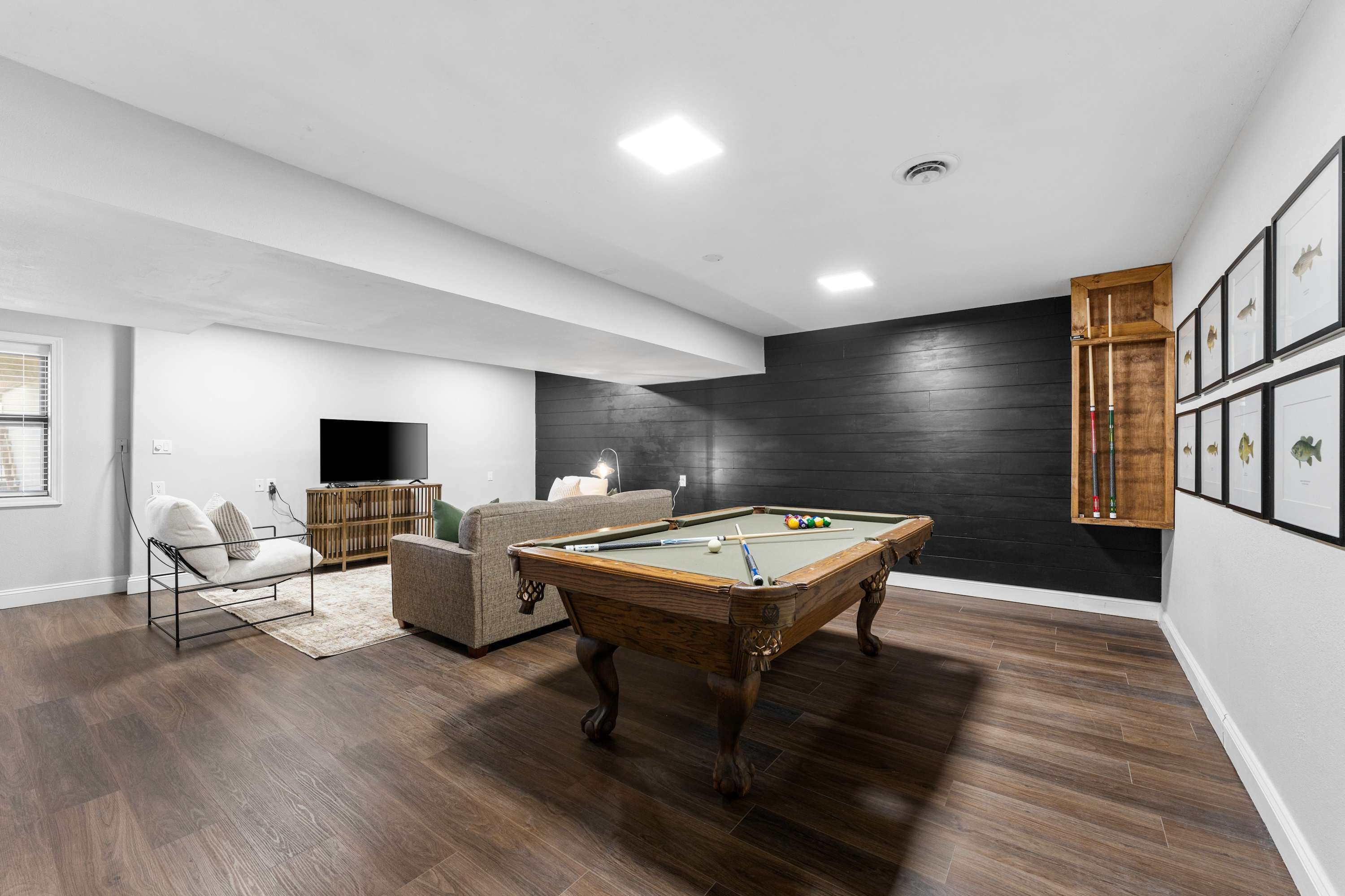 Uma sala de estar moderna com mesa de bilhar, um sofá e uma televisão.