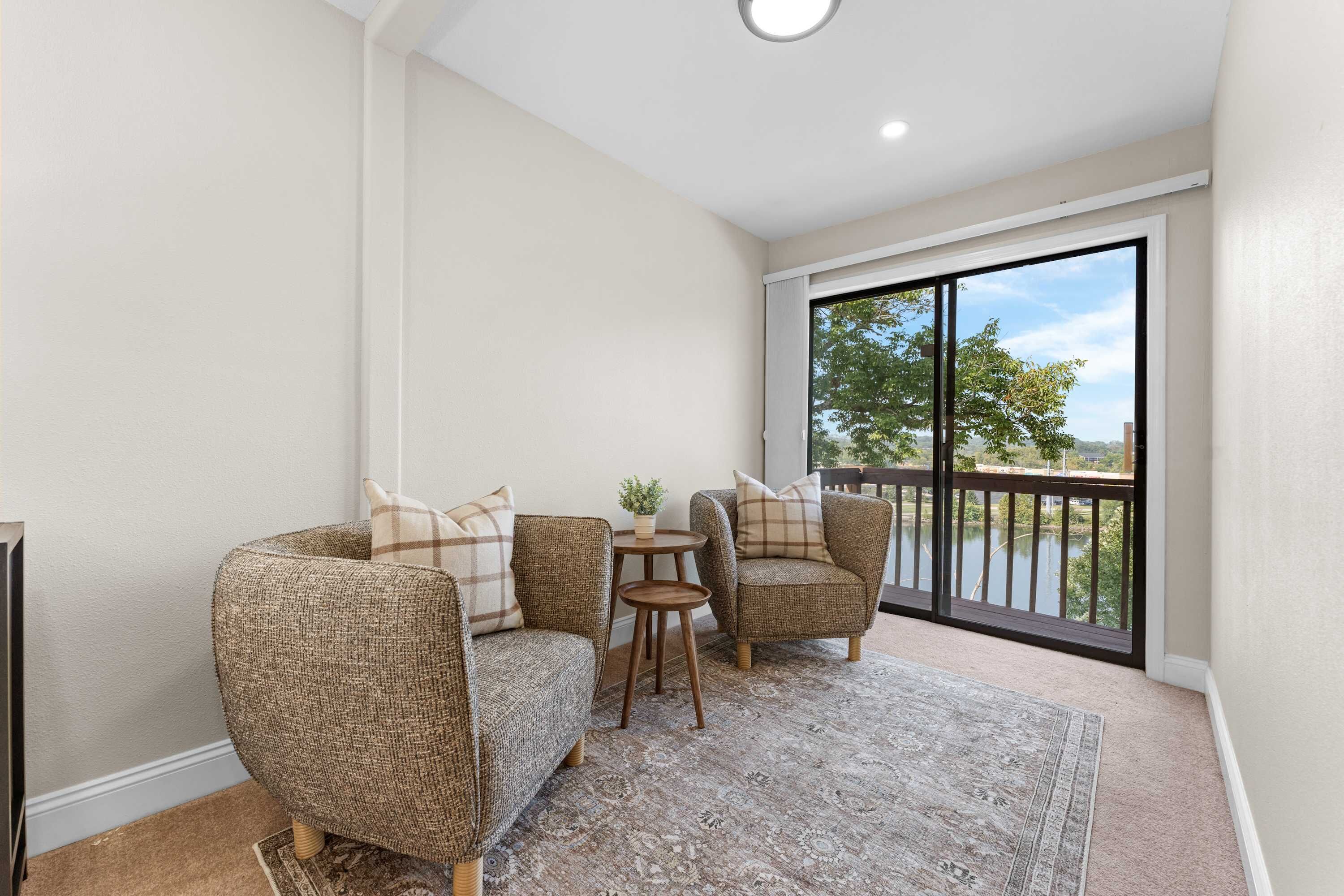 A balcony with wicker furniture, a small table, and a view of a lake.