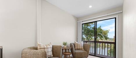 A balcony with wicker furniture, a small table, and a view of a lake.