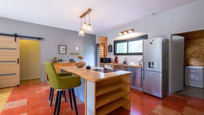 A modern kitchen with a central island, wooden cabinets, and a built-in oven. - Chemin de Ronze - Maison au calme avec piscine (Labastide-de-Virac)