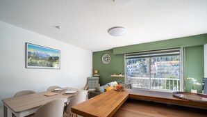 Un comedor con una mesa de madera, sillas y vistas a edificios a través de un ventanal grande.