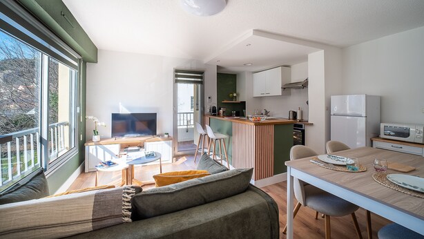 Un apartamento moderno con sala de estar, comedor, kitchenette y balcón.