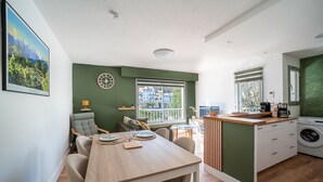 Una cocina moderna con comedor, lavadora y un amplio ventanal con vistas a edificios.