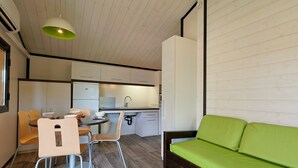 Une cuisine compacte avec un coin repas, un canapé vert et un plafond en bois.