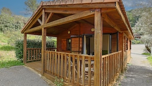 Une cabane en bois dotée d’un porche et d’une terrasse couverte.