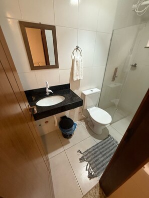 Une salle de bain équipée d’un lavabo, d’un miroir, de toilettes et d’une douche.