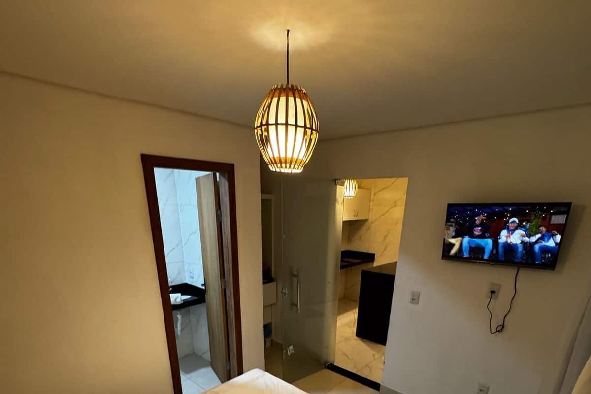 Een slaapkamer met een bed, een aan de muur bevestigde televisie en een badkamer die door een open deur zichtbaar is.