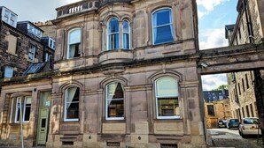 Un edificio histórico con múltiples ventanas, una puerta verde y fachada de piedra.