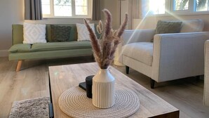 Una sala de estar con un sofá, una mesa de centro con un florero y una lámpara.