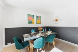 A dining area with a table set for four, teal chairs, and abstract wall art. - A Boutique 4 bed House in Bath - Parking (Bath)