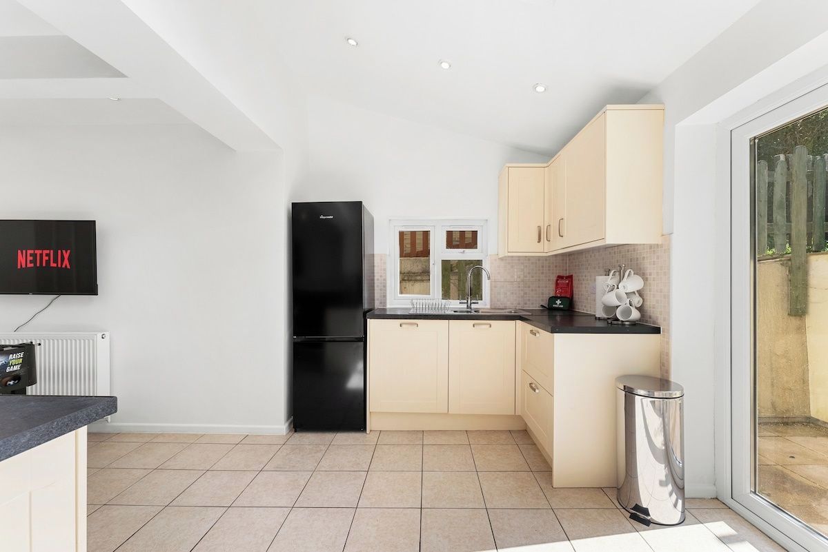 A modern kitchen with a black refrigerator, a sink, and a window.