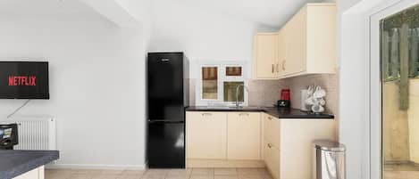 A modern kitchen with a black refrigerator, a sink, and a window.