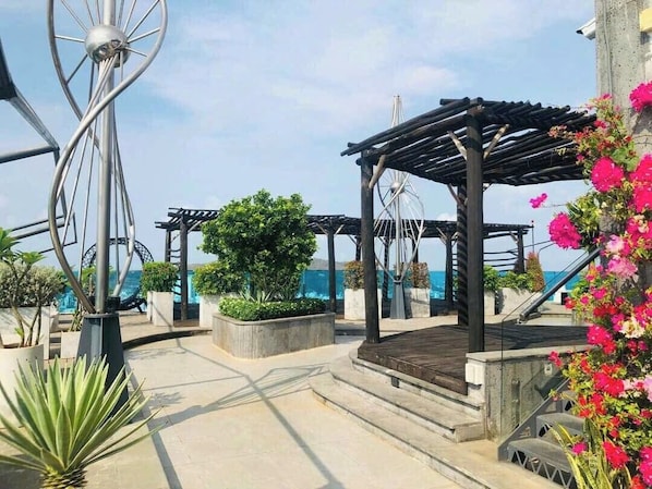 Una terraza en la azotea con pérgola, una noria y vistas al mar.