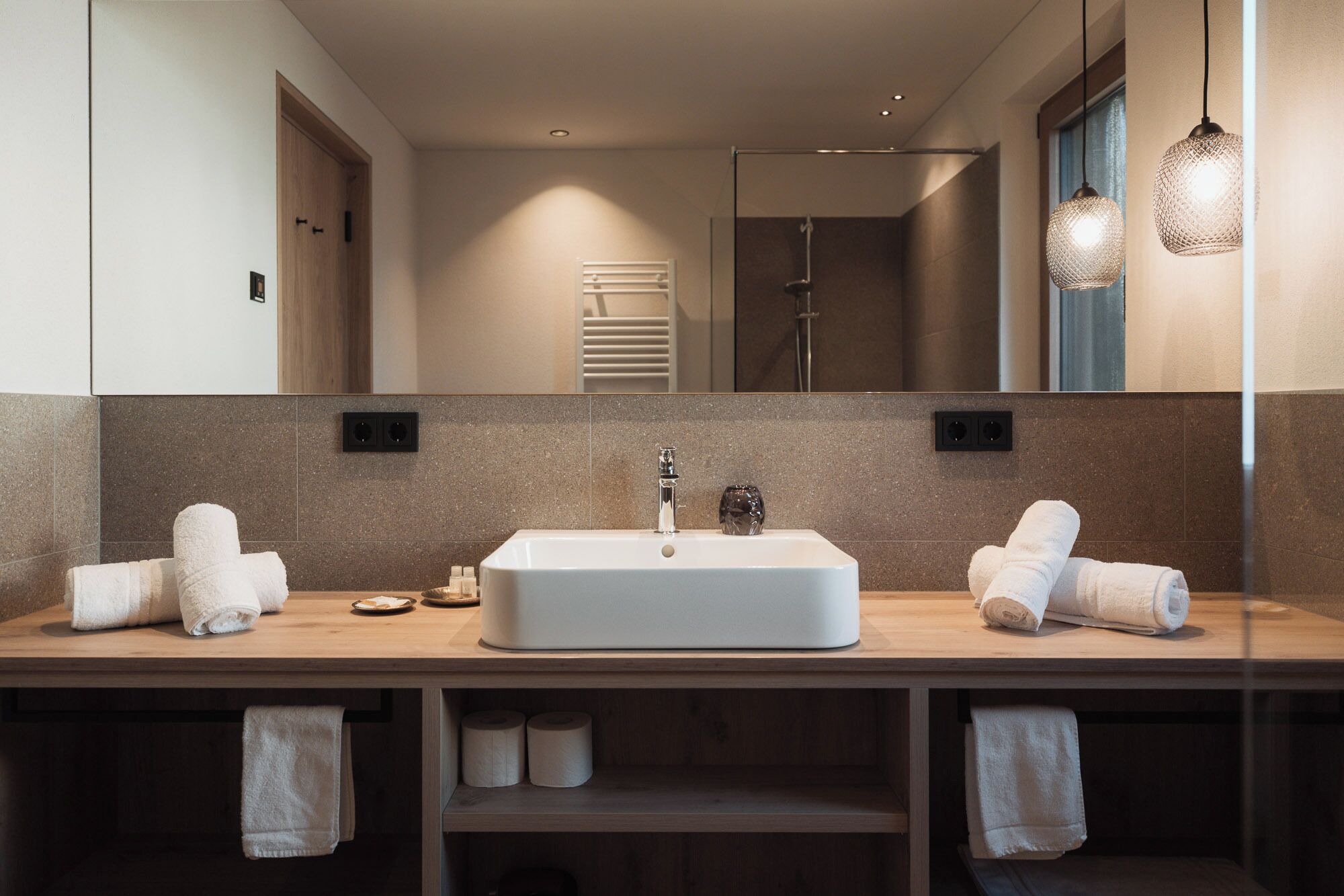 Un baño moderno con un lavamanos rectangular grande, dos toalleros y un espejo.
