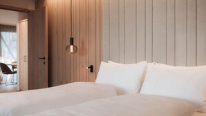 A hotel room with two beds, wooden panel walls, and a hanging light fixture. - Mountain Residence CLARA (Brunico)