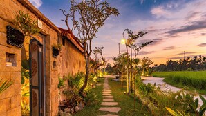 A stone building with a number "102" sign, a stone pathway, and lush greenery. - Arindama Villa Ubud by Dhananjaya Hospitality (Sebatu)