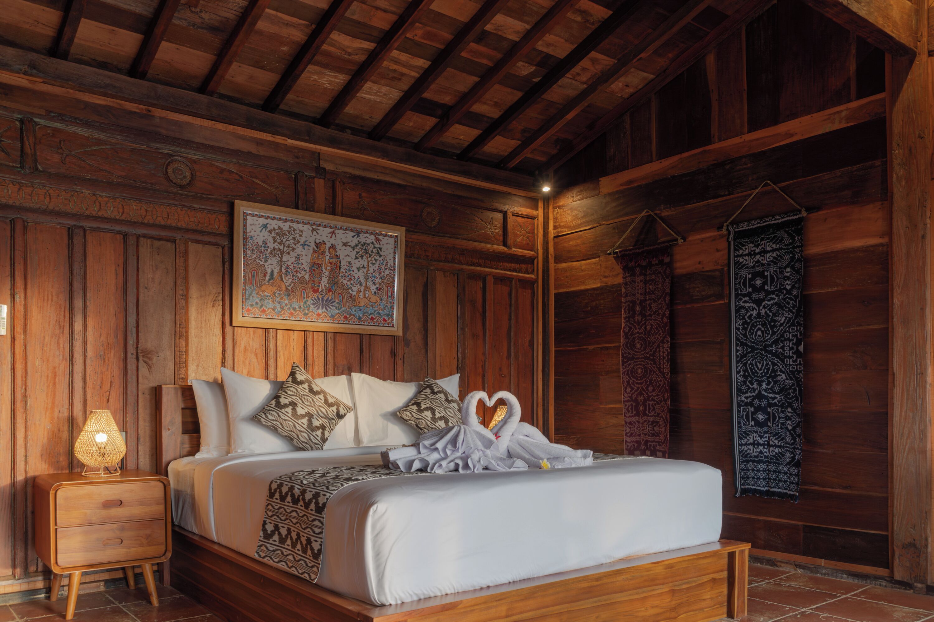 A wooden-paneled bedroom with a bed, pillows, a nightstand, and a wall tapestry.