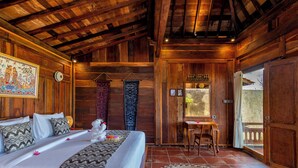 A wooden room with a bed, a small table, and a chair. - Arindama Villa Ubud by Dhananjaya Hospitality (Sebatu)