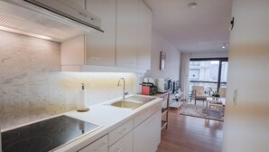 A modern kitchen with a built-in stove, a sink, and white cabinetry. - Studio by the Beach With Sea View (Koksijde)