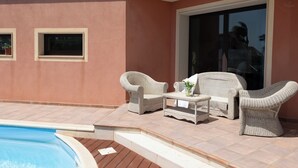 A poolside area with wicker furniture, a small table, and a chair. - Villa Stephanie with pool (Marina di Ragusa)