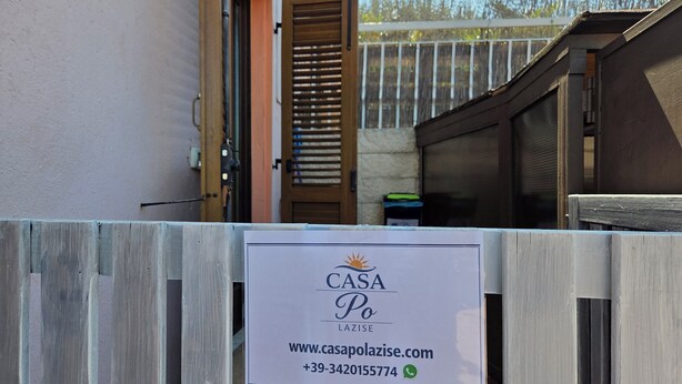 A wooden fence with a sign for CASA PO LAZISE, including a website and phone number. - PO LAZISE HOUSE (Lazise)
