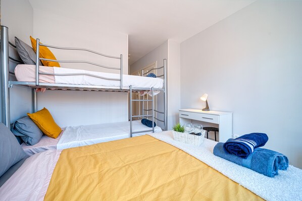 Habitación con literas, escritorio, lámpara y una planta pequeña.