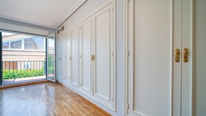 Ein geräumiger Raum mit Holzboden, großen weißen Türen und einer Glastür, die auf einen Balkon führt.