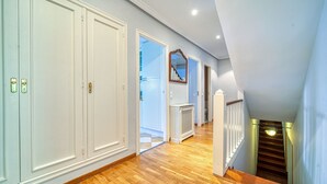 Ein Flur mit Holzboden, weißen Türen und einer Treppe mit Geländer.