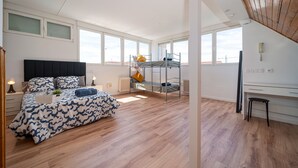 Ein geräumiges Schlafzimmer mit Etagenbett, Schreibtisch und großem Fenster.