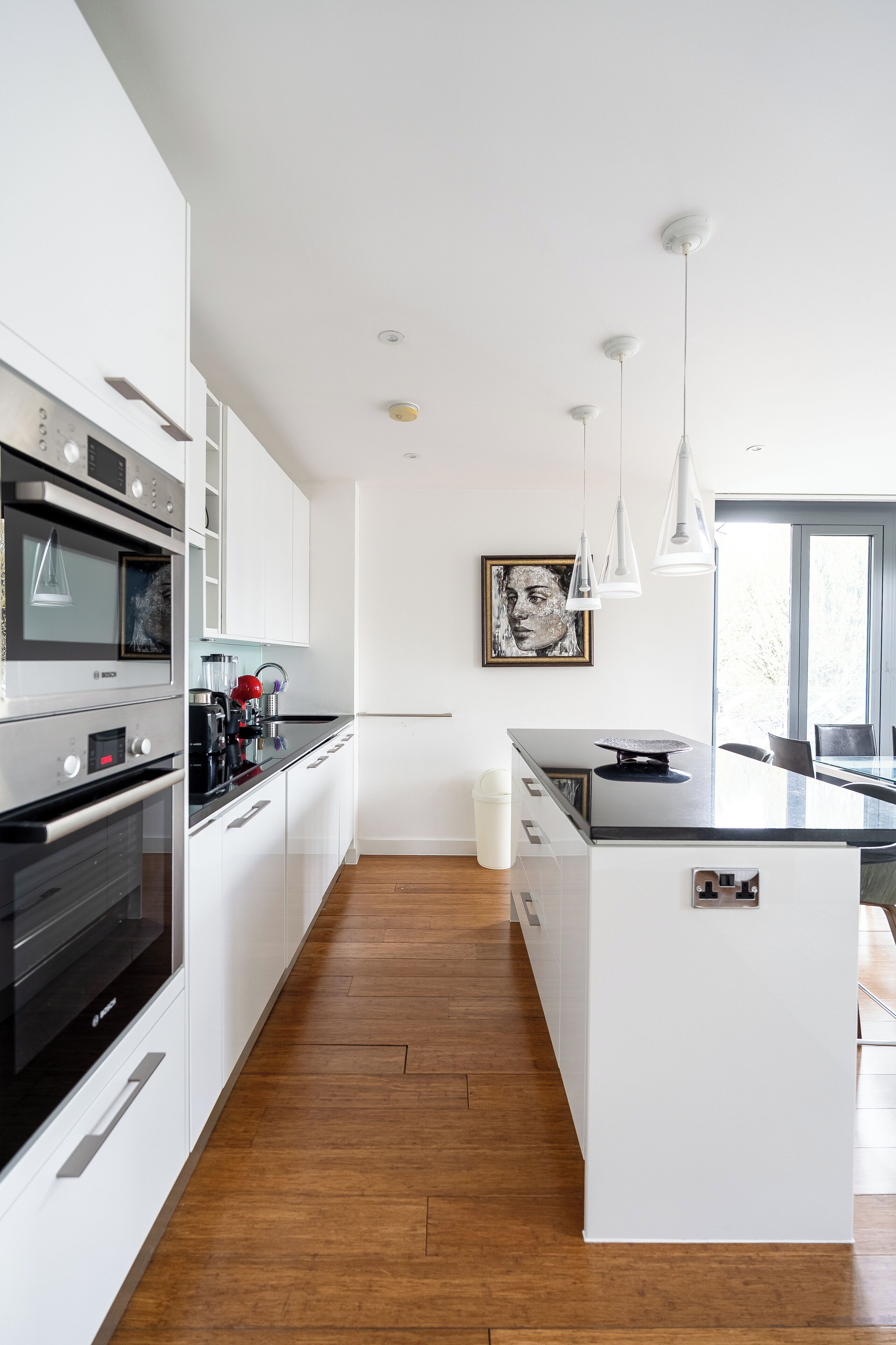 Een moderne keuken met witte kasten, een groot eiland en roestvrijstalen apparatuur.