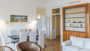 A dining area with a table and chairs, a painting on the wall, and a display cabinet with glass shelves. - Amazing Piazza Fiume (Roma)