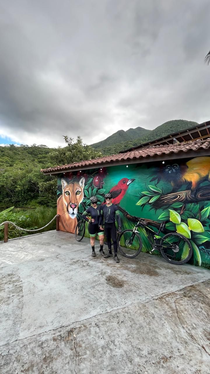 A mural with a lion, birds, and cyclists on a building with a tiled roof.