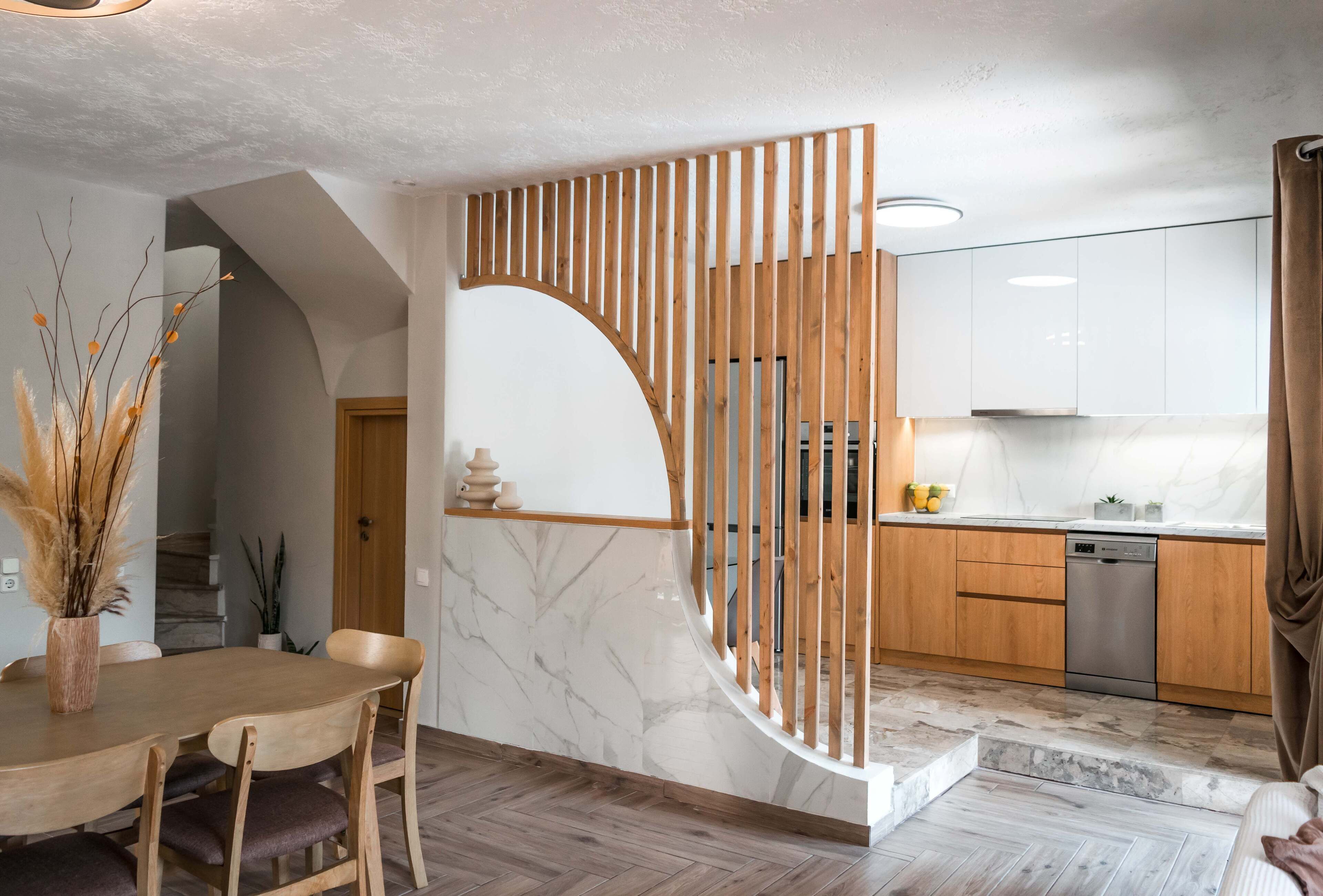 A modern kitchen with wooden cabinets, a stainless steel dishwasher, and a marble island.