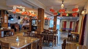 Ein Restaurant mit Holztischen und -stühlen, einer Bar und einer Bühne.