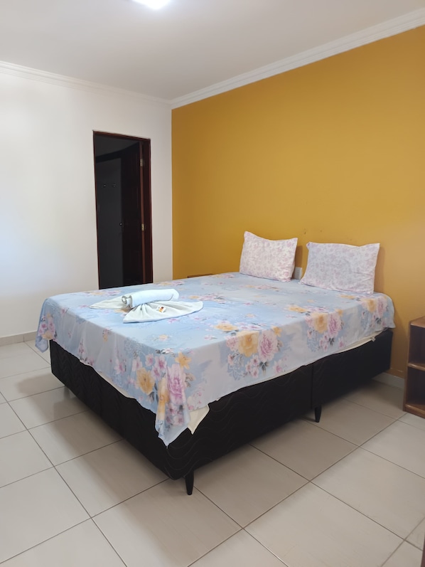 Un dormitorio con cama, dos almohadas, una mesita de noche y una puerta.