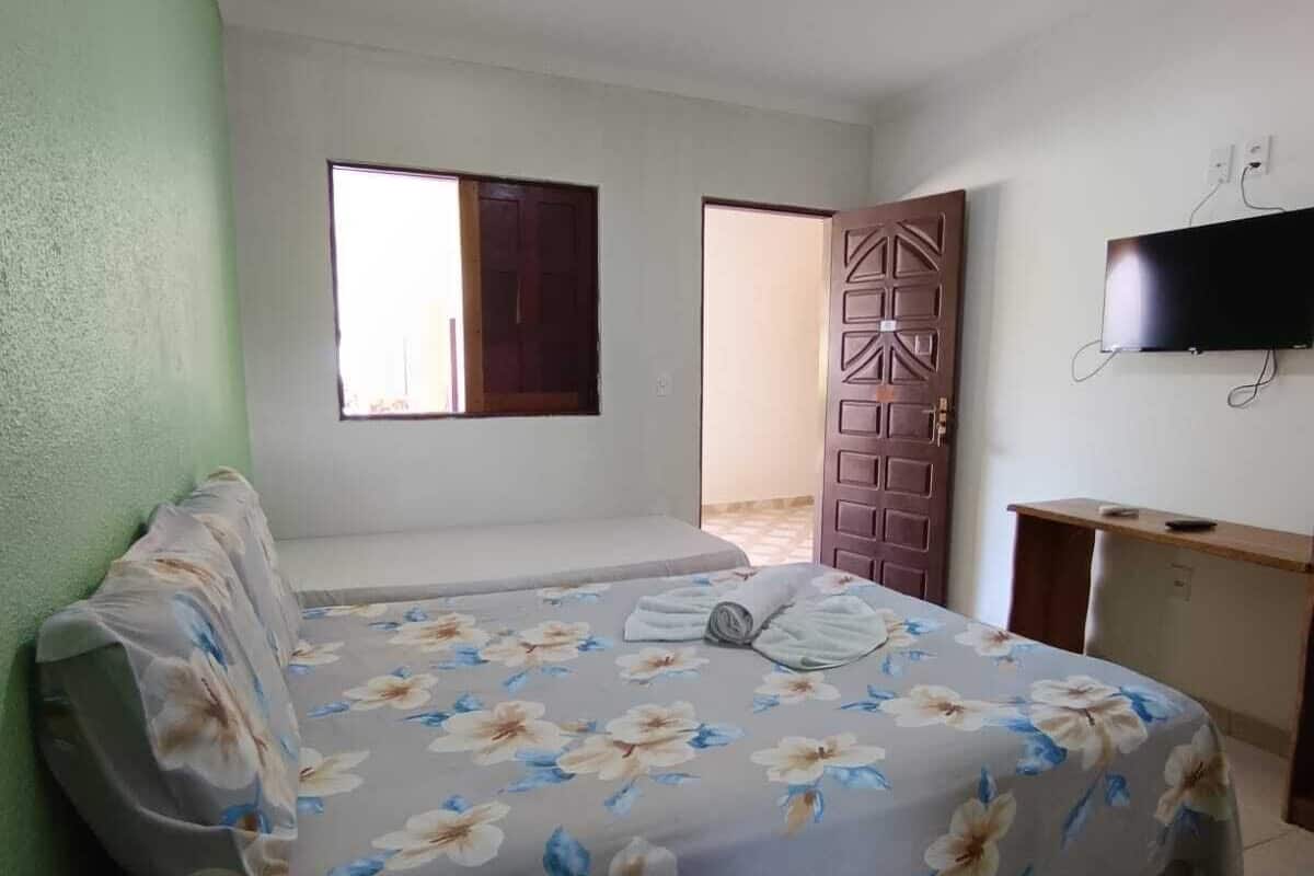 A bedroom with a bed, a desk, a television, and a door.