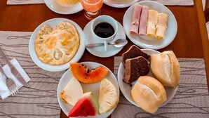 A breakfast table with plates of eggs, toast, fruit, and juice. - Pousada Praia dos Corais (Paripueira)