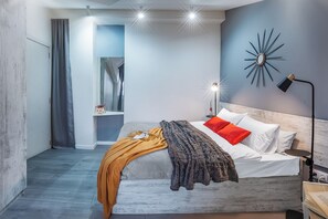 A modern bedroom with a bed, a nightstand, a wall-mounted lamp, and a decorative mirror.