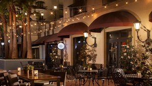 An outdoor dining area with string lights, tables, chairs, and potted plants.