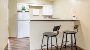 Una cocina compacta con un refrigerador blanco, dos taburetes de bar y una pequeña isla.