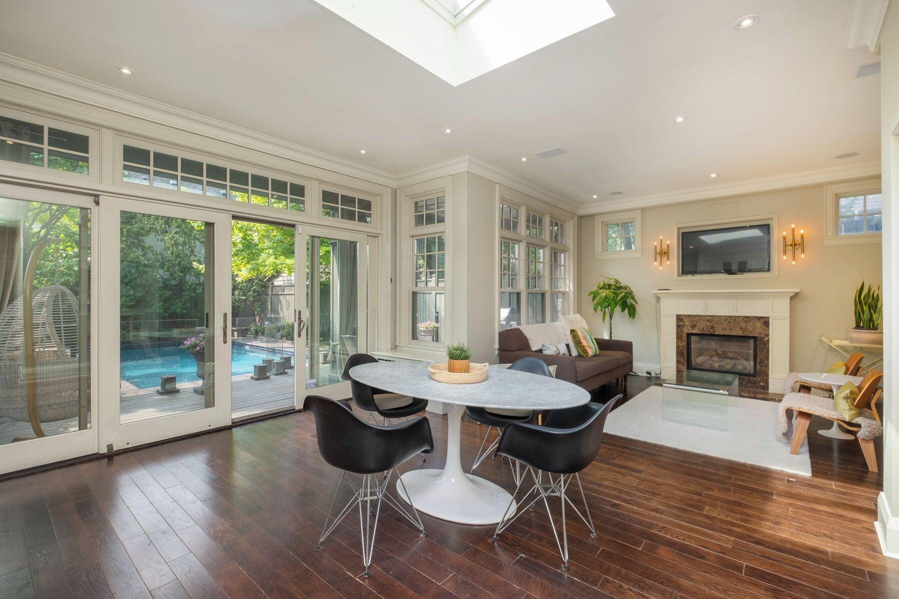 A spacious living room with a large dining table, comfortable seating, a fireplace, and a TV.