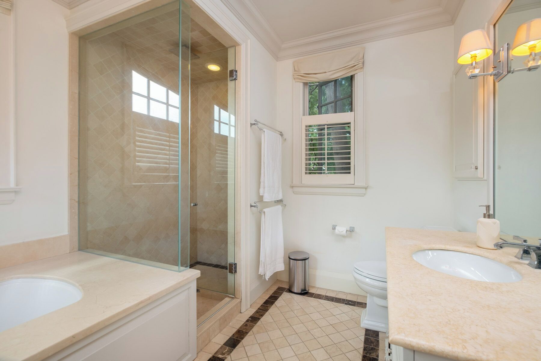 A bathroom with a glass-enclosed shower, a toilet, and a sink with a mirror.