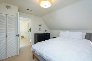 Une chambre à coucher avec un lit, une commode, une porte et un luminaire au plafond.