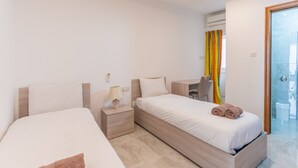 A hotel room with two beds, a desk, and a bathroom. - Maltese Cozy Studio Apartment (SAN PAWL IL-BAĦAR)