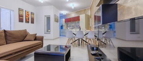 Relax in this stylish living room with a sofa, flat-screen TV, dining area, and fully equipped kitchen.