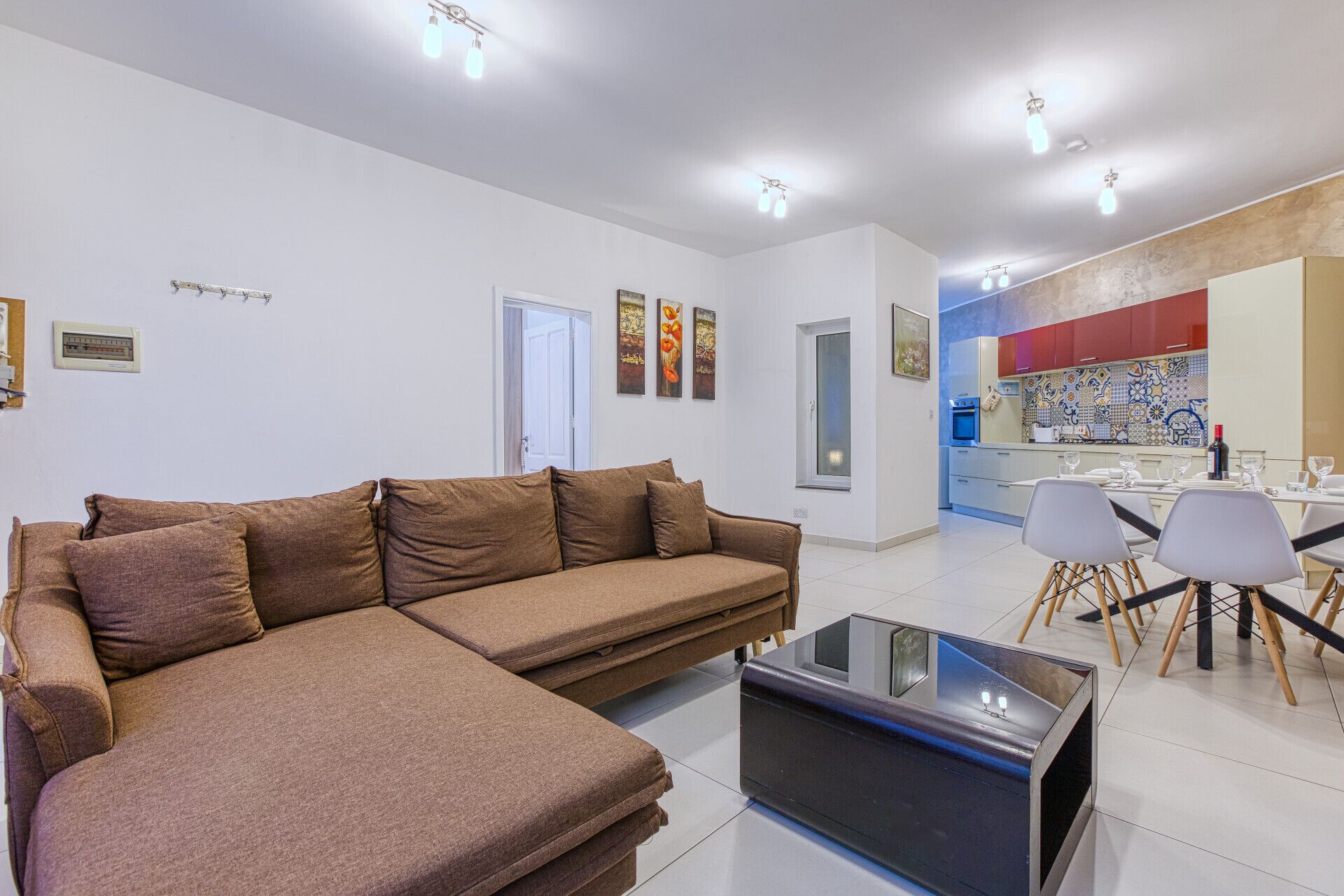 A modern living room with a sectional sofa, a glass coffee table, and a dining area with chairs and a table.