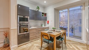 A modern kitchen with built-in appliances and a dining area with a wooden table and chairs. - Valletta in Style beautiful apartment (IL-BELT VALLETTA)