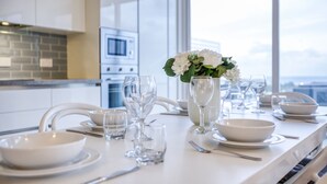 Een moderne keuken met witte kasten, een groot raam en een eettafel gedekt voor een maaltijd.