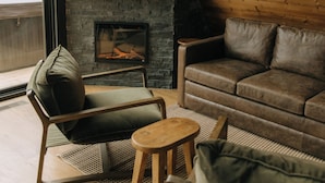 A cozy living room with a fireplace, leather sofa, and a television displaying "NETFLIX".